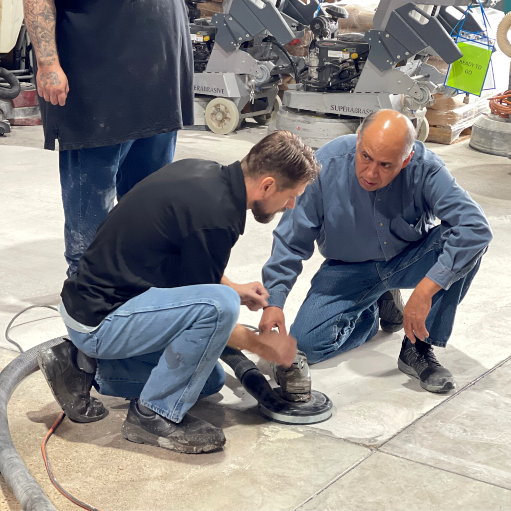 Two men working on a motorcycle in an indoor area.
