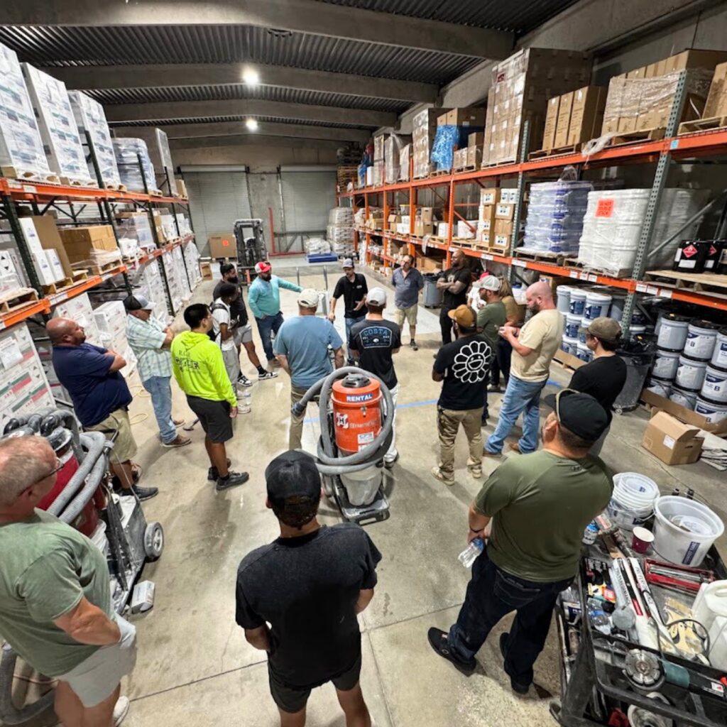 A group tour inside a warehouse filled with shelves and goods.