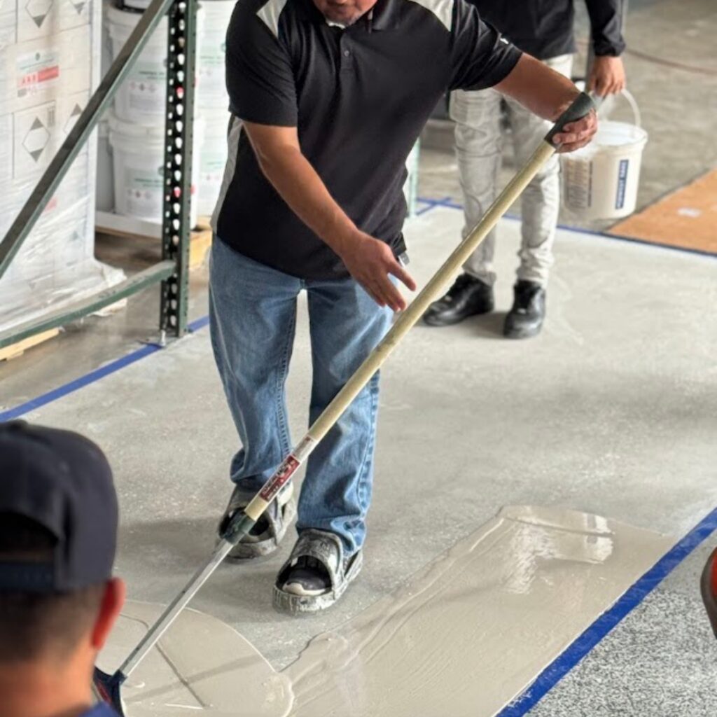 Person smoothing wet concrete with a long-handled tool.
