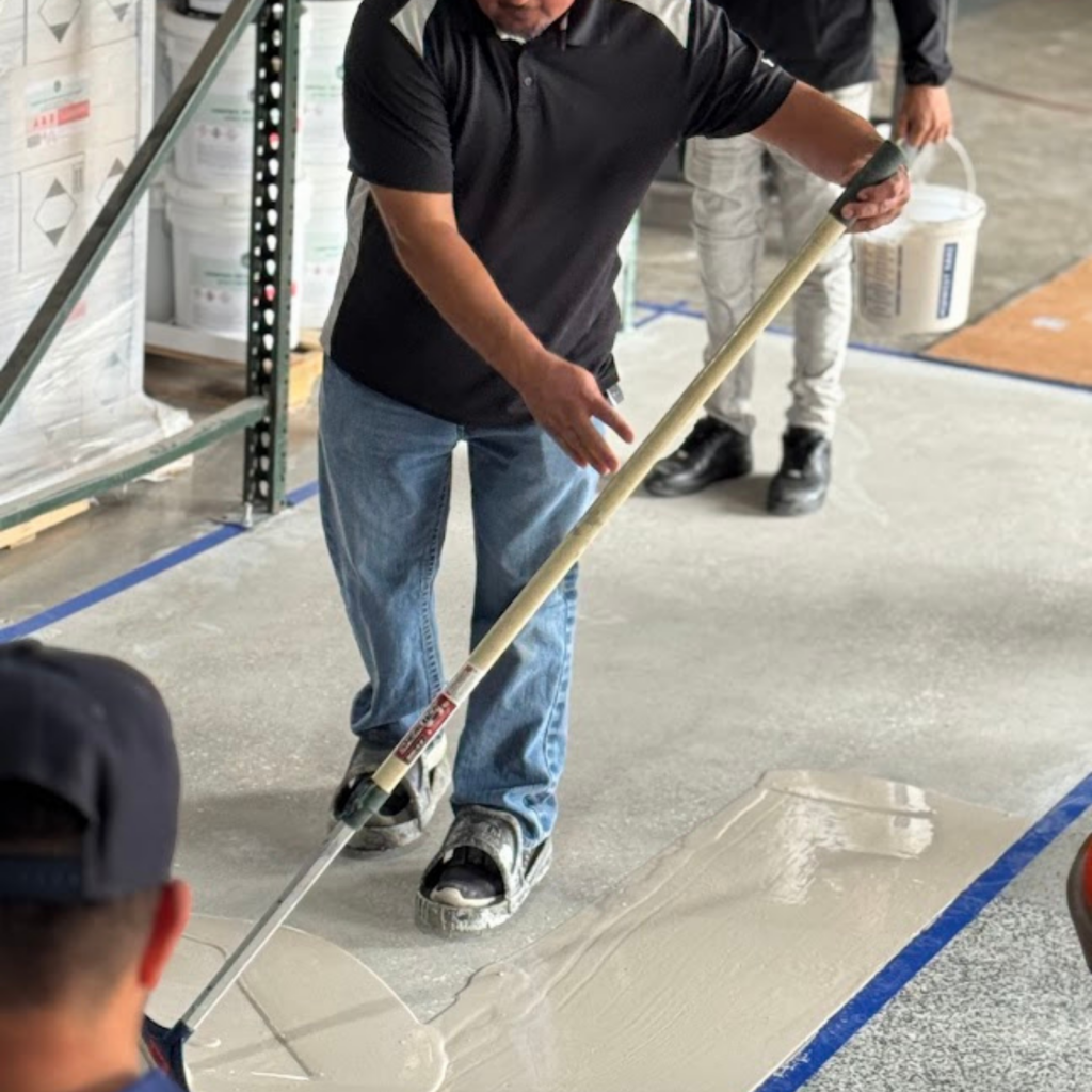 Person smoothing wet concrete with a long-handled tool.