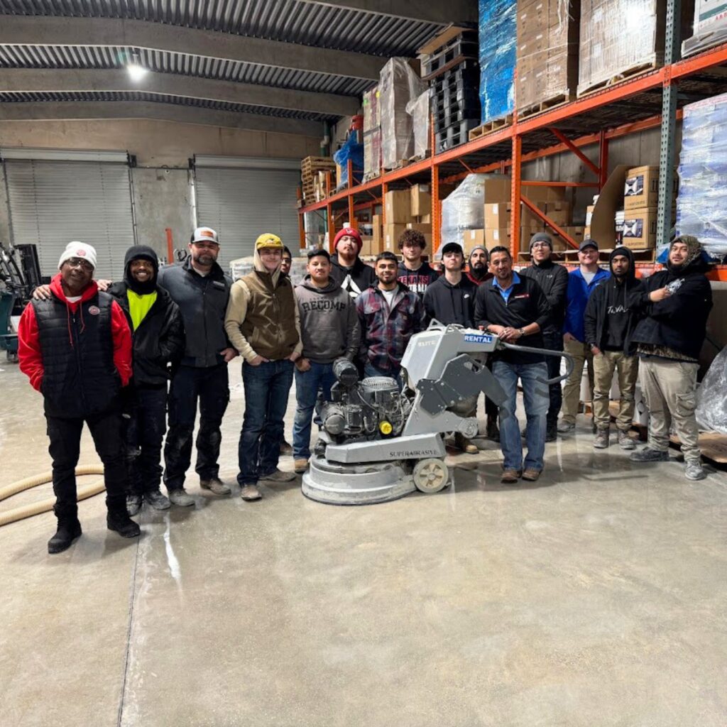 A group of workers posing in a warehouse with cleaning equipment.